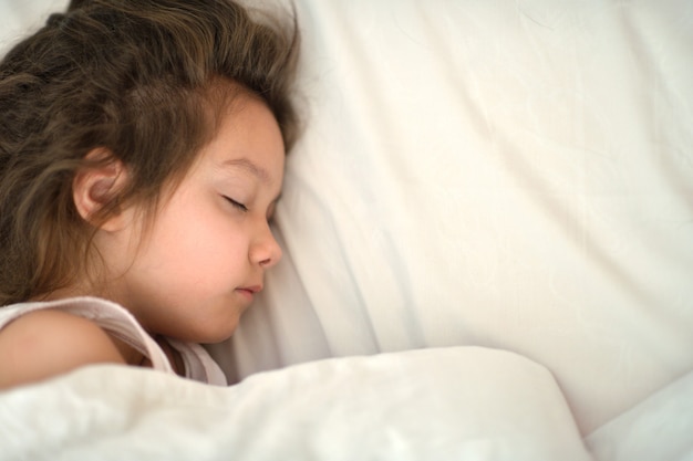 Retrato de una linda niña durmiendo en la cama