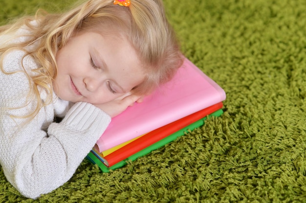 Retrato de linda niña durmiendo sobre una pila de libros