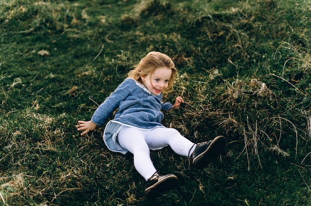 Retrato de una linda niña hermosa y feliz corriendo por el campo soleado