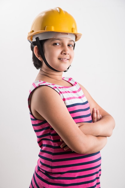 Retrato de linda niña india en amarillo sombrero duro sosteniendo rollo de papel, que se encuentran aisladas sobre fondo blanco.