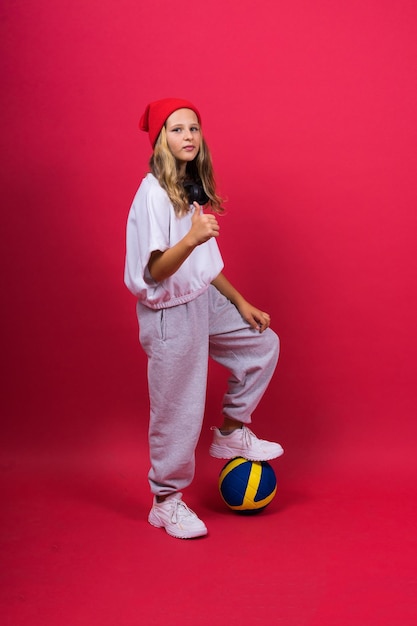 Retrato de una linda niña de ocho años vestida de voleibol aislada en un fondo rojo