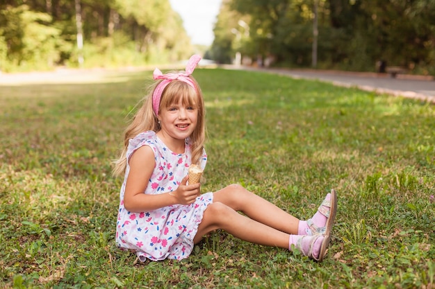 Retrato de una linda niña rubia con helado en un paseo por el parque.