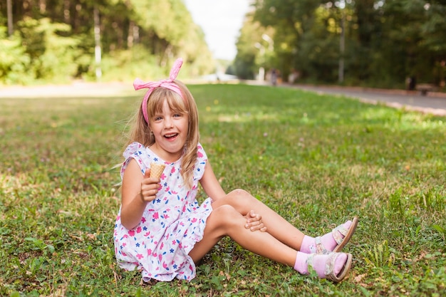 Retrato de una linda niña rubia con helado en un paseo por el parque.