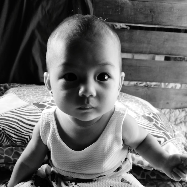 Foto retrato de una linda niña sentada en la cama en casa