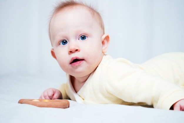 Retrato de una linda niña de siete meses con ojos azules. Un niño juega con juguetes de madera en una habitación luminosa. Juguetes ecológicos para niños fabricados con materiales naturales.