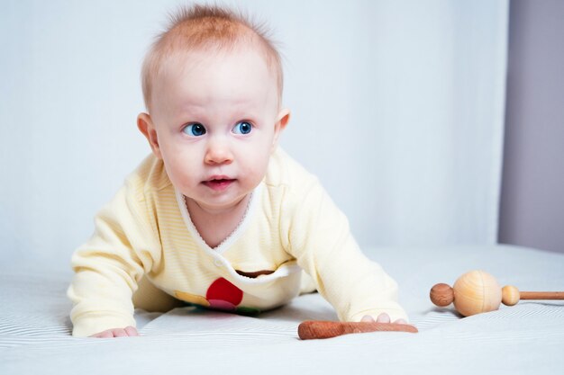 Retrato de una linda niña de siete meses con ojos azules. Un niño juega con juguetes de madera en una habitación luminosa. Juguetes ecológicos para niños fabricados con materiales naturales.