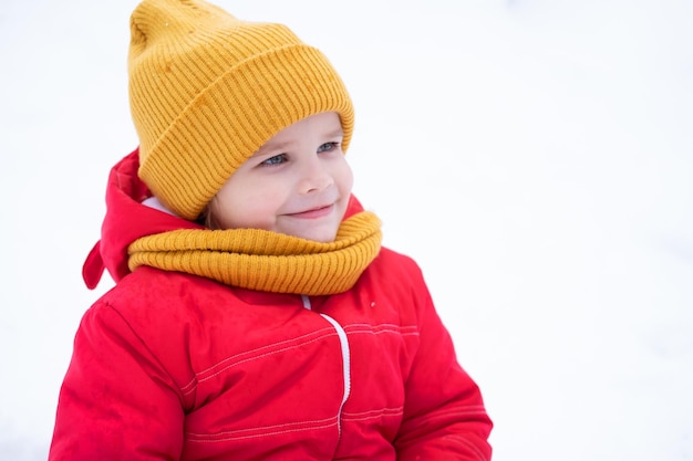 retrato de una linda niña sonriente feliz con traje de nieve rosa caminando en el bosque de invierno