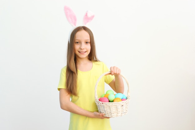Retrato de una linda niña sonriente con orejas de conejo y huevos de pascua en las manos