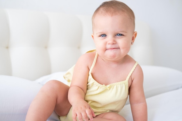 retrato de una linda niña sonriente con traje amarillo sobre ropa de cama blanca. Niño recién nacido sano