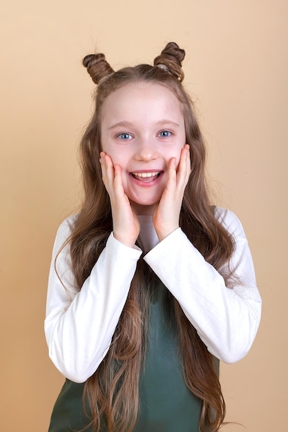 Retrato de una linda niña sorprendida con el pelo largo sobre un fondo beige Miro a la cámara Publicidad de productos para niños