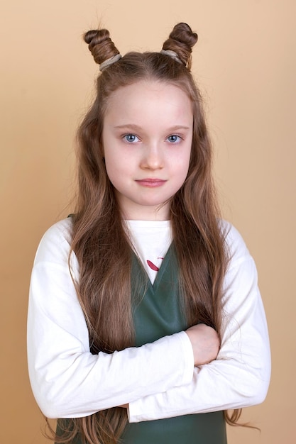 Retrato de una linda niña sorprendida con el pelo largo sobre un fondo beige Miro a la cámara Publicidad de productos para niños