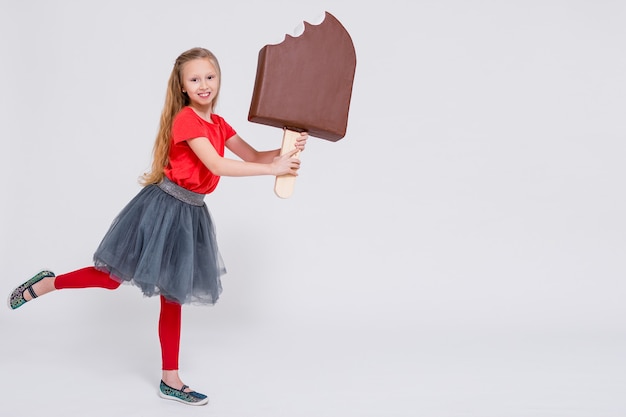 Retrato de linda niña sosteniendo un enorme helado y copie el espacio sobre fondo blanco.