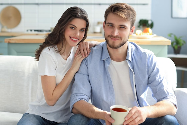 Retrato de linda pareja joven sentada en el sofá.