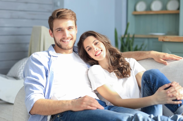 Retrato de linda pareja joven sentada en el sofá.