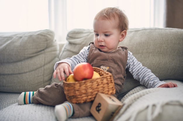 Retrato de un lindo bebé de 1 año sentado en un sofá