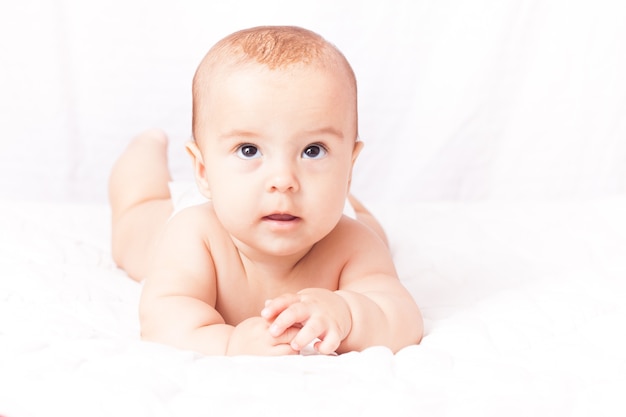 Retrato de un lindo bebé acostado sobre el textil blanco