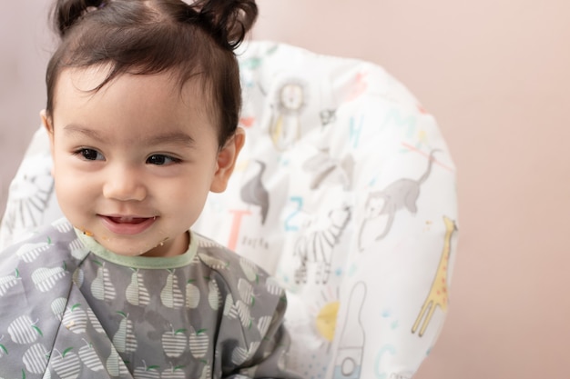 Retrato de lindo bebé asiático que está feliz sentado en shair y sonríe con espacio de copia, concepto de expresión de bebé