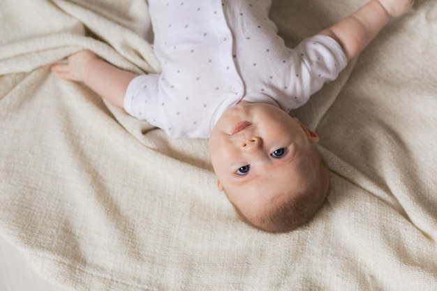 Retrato de un lindo bebé recién nacido con ropa ligera sobre una colcha de lino gris. productos para niños. concepto de sueño saludable y desarrollo infantil. infancia feliz, maternidad. foto de alta calidad