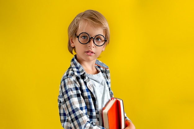 Retrato de lindo e inteligente muchacho rubio caucásico en una camisa a cuadros sobre fondo amarillo.