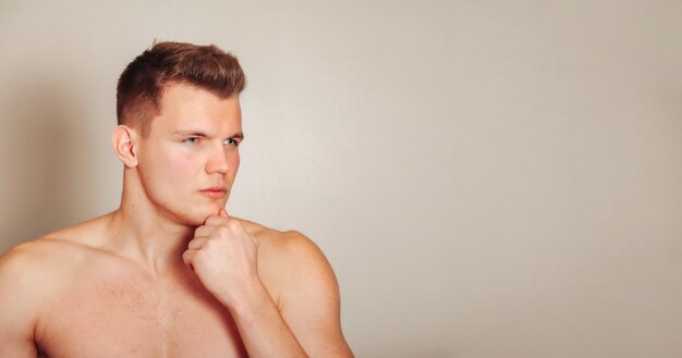 Foto retrato de lindo joven de complexión atlética sobre fondo claro aislado. hombre guapo y musculoso