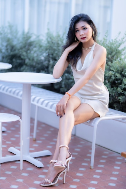 Retrato lindo modelo de moda de mulher de negócios de pessoas asiáticas em vestido sem mangas branco de verão e café em xícara na cafeteria