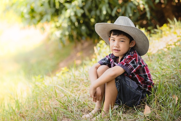 Retrato lindo niño asiático sentado en la hierba