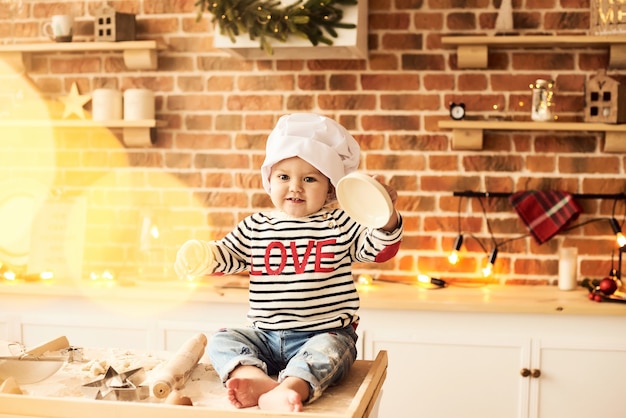 Un retrato de un lindo niño cocinado y jugado con harina y masa en la cocina.