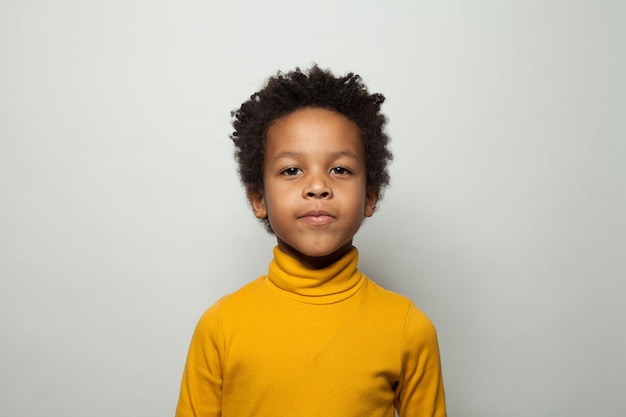 Retrato de un lindo niño negro sonriendo sobre un fondo blanco