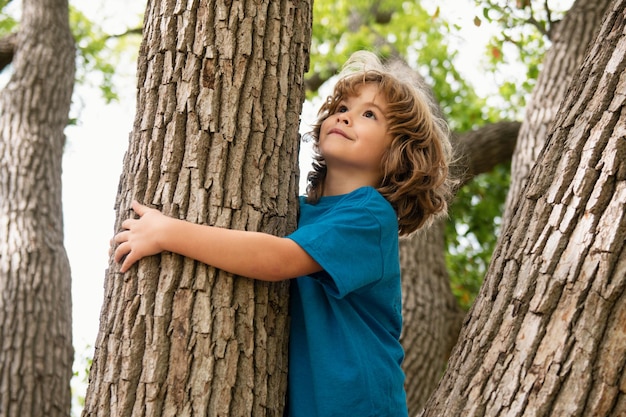 Retrato de un lindo niño trepando a un árbol en un parque