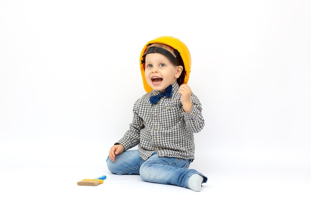 Retrato de un lindo niño vistiendo casco de gran tamaño y cepillo aislado sobre blanco