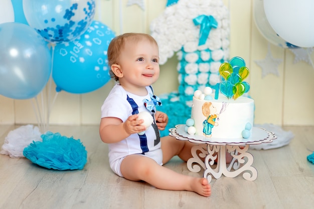 Bebé de 1 año en un estudio fotográfico con un pastel y globos