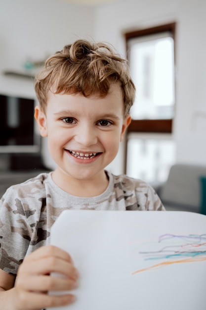 Retrato de un lindo y sonriente niño en edad escolar haciendo muecas y mirando a la cámara