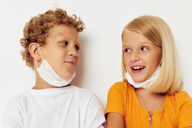 Retrato de lindos niños divertidos máscara médica stand lado a lado closeup estilo de vida inalterado