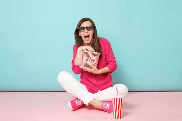 Retrato de longitud completa mujer divertida en camisa rosa, pantalón blanco sentado en el piso viendo una película