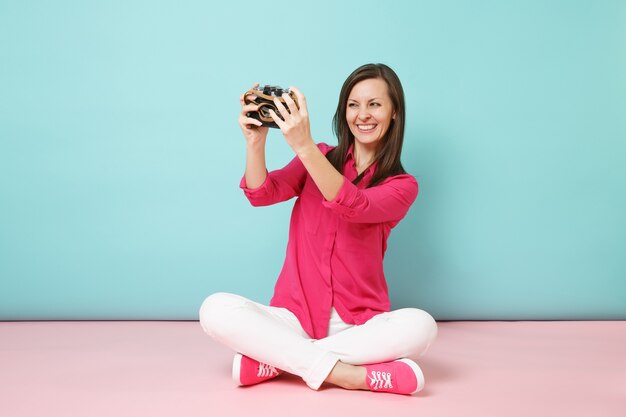 Retrato de longitud completa mujer joven en camisa rosa blusa pantalón blanco sentado en el suelo mantenga la cámara