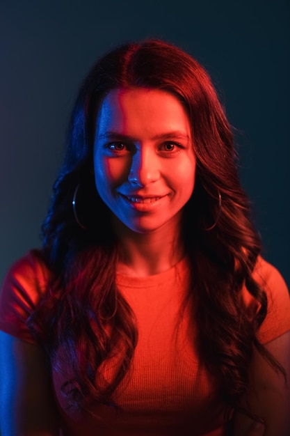 Retrato de luz de color Iluminación moderna Estilo de vida futurista Atractiva cara de niña sonriente en brillante colorido brillante rojo azul neón led brillo aislado sobre fondo oscuro