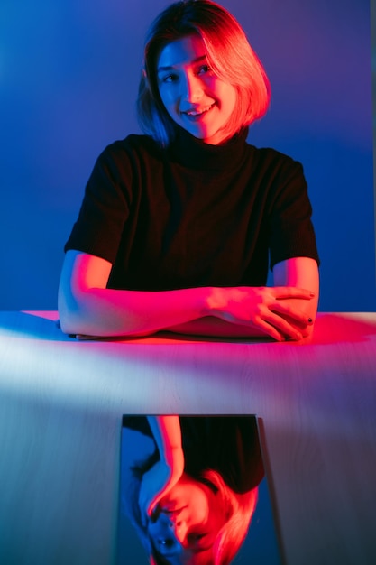 Retrato de luz de neón de doble cara fingiendo una linda y curiosa chica sonriente con cara aburrida e indiferente