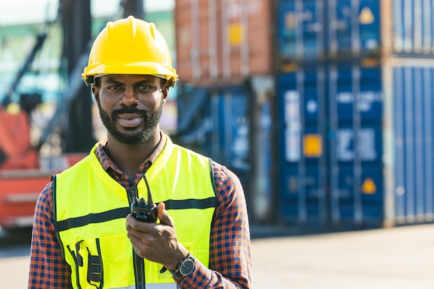 Retrato macho negro africano ingeniero capataz de trabajador en control de patio de contenedores carga de carga