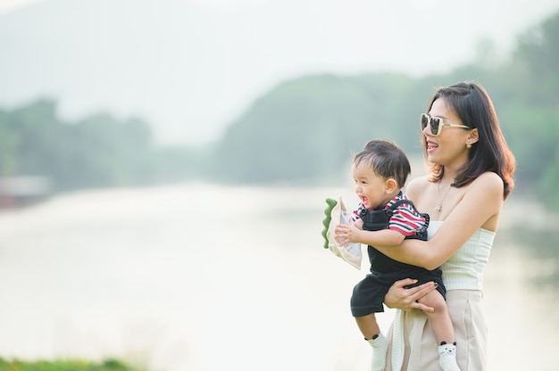 Retrato de una madre asiática sonriendo con su bebé de 11 meses al aire libre