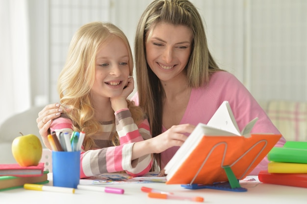 Retrato de madre ayudando a su pequeña hija con la tarea