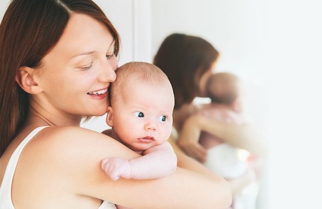 Retrato de la madre y el bebé Hermosa mujer sosteniendo a un bebé en sus brazos