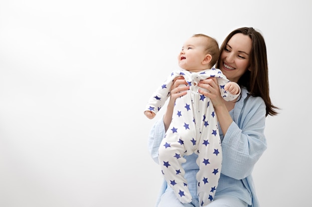 Retrato de madre y bebé mujer morena sonriente abraza y sostiene al bebé