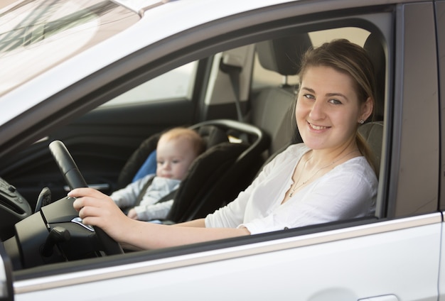 Retrato, de, madre, coche que conduce, con, pequeño, nene, sentado, en, asiento de seguridad