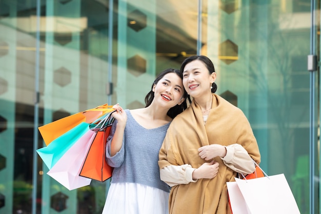 Retrato, de, un, madre e hija, ambulante, con, bolsas de compras