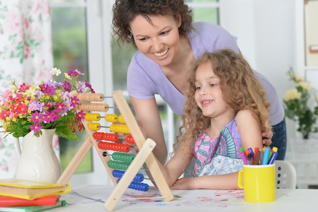 Retrato de una madre e hija contando, haciendo los deberes