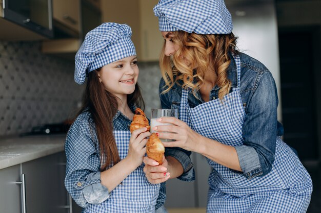 Retrato de madre e hija con cruasanes y leche. Concepto de familia