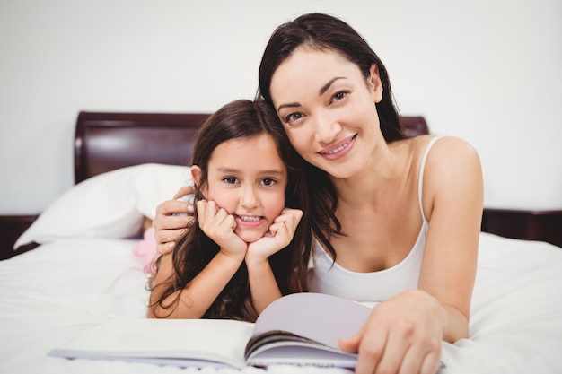 Retrato de madre e hija con el libro en la cama en su casa