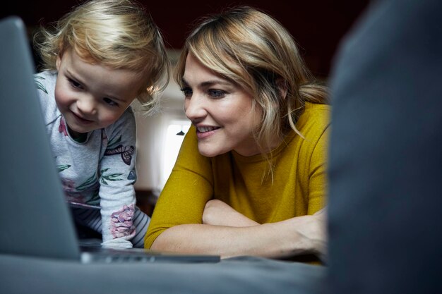 Retrato de madre e hija mirando portátil en casa