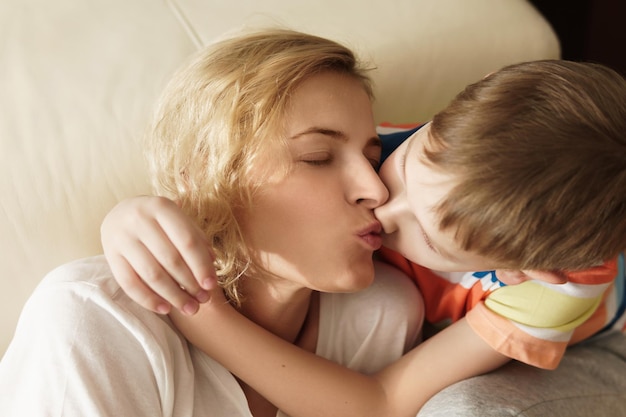 Retrato de madre e hijo encantadores besándola en casa