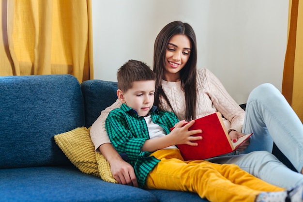 Retrato de madre e hijo leyendo un libro en casa